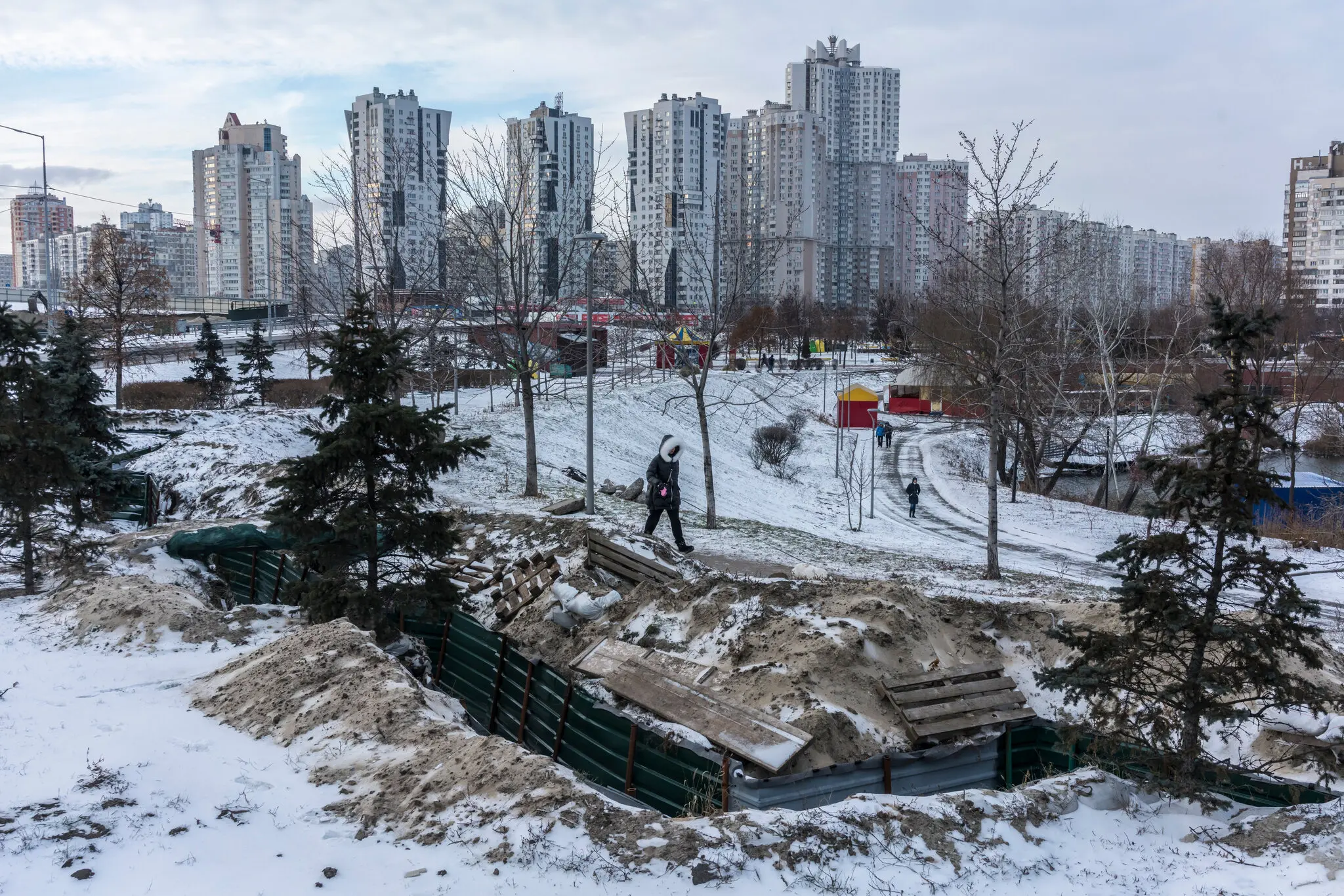 Жінка проходить повз оборонний окоп із перших днів російського вторгнення, Київ 11 січня.